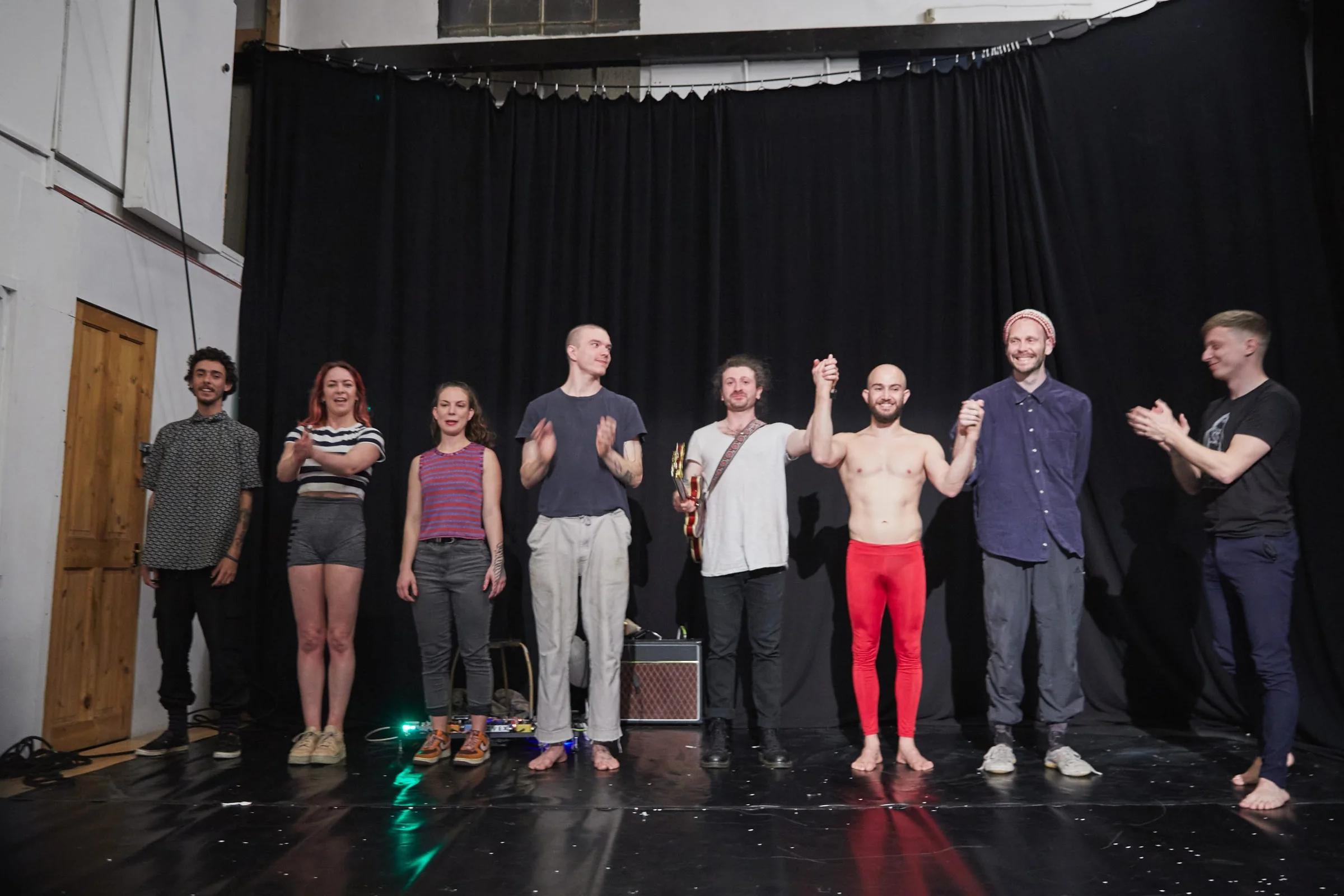 A line of performers and musicians taking a curtain bow.